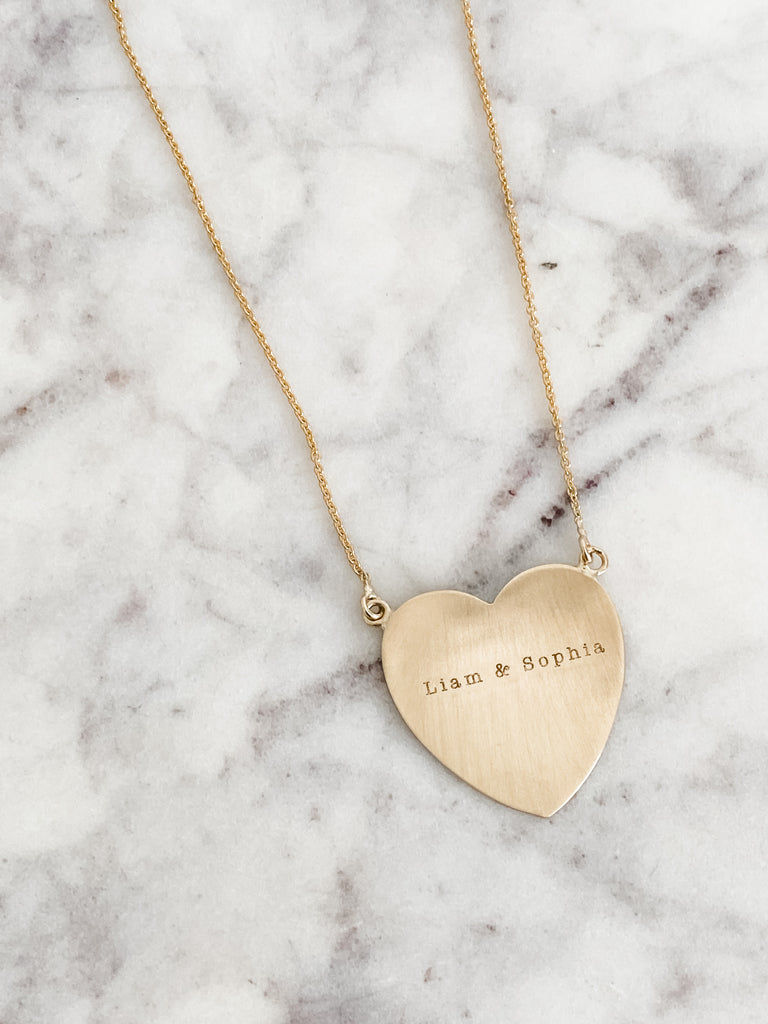 A bold piece showing your love! Let's engrave your favorite names or quotes and make it set in gold!  Details:  Heart measures approximately one inch Offered in Brushed and Shiny finish. (pictured in Brushed finish)  Offered in 14K Yellow Gold, 14K Rose Gold, and 14K White Gold Typewriter font will be used to personalize with your favorite name or quote Please allow 2-3 weeks for production time. Please let us know what you would like for it to say in the NOTE section upon checkout.
