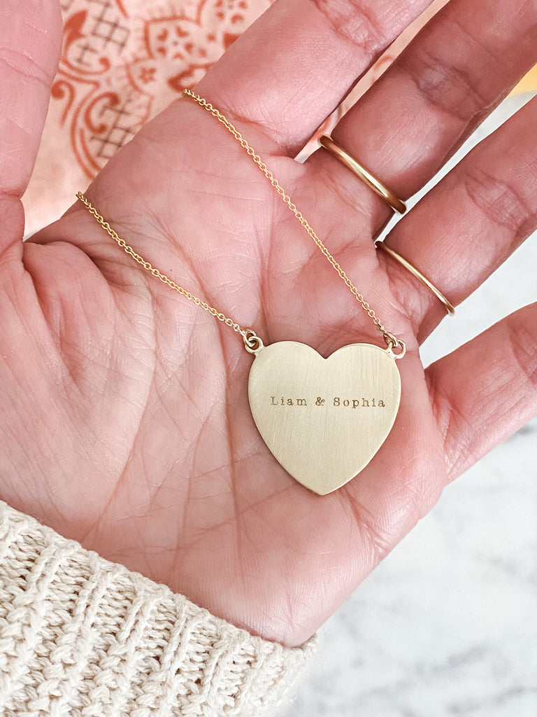 A bold piece showing your love! Let's engrave your favorite names or quotes and make it set in gold!  Details:  Heart measures approximately one inch Offered in Brushed and Shiny finish. (pictured in Brushed finish)  Offered in 14K Yellow Gold, 14K Rose Gold, and 14K White Gold Typewriter font will be used to personalize with your favorite name or quote Please allow 2-3 weeks for production time. Please let us know what you would like for it to say in the NOTE section upon checkout.